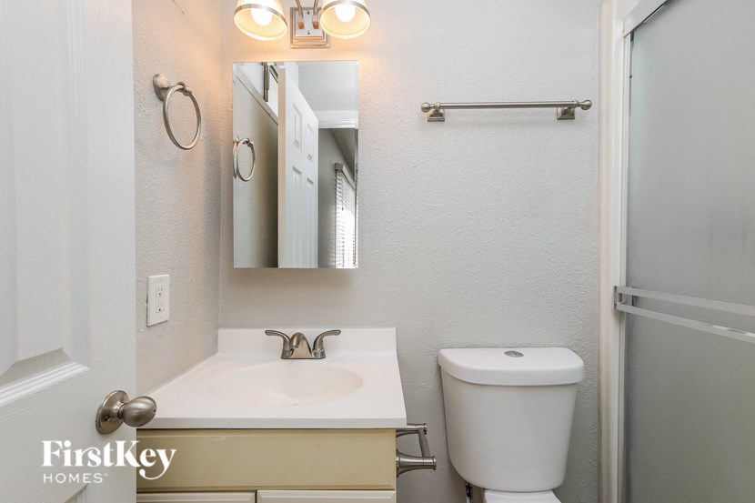 a bathroom with a toilet sink and mirror and a shower