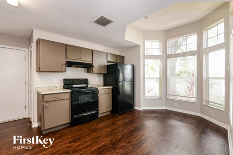 A kitchen with a black fridge and stove top oven.