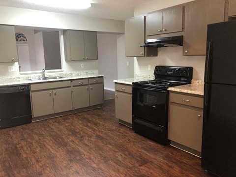 A kitchen with black appliances and wooden floors.