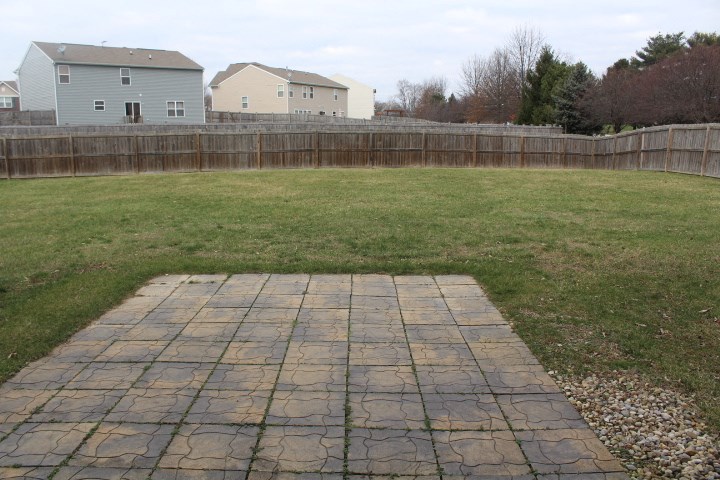 a backyard with a stone walkway and a fence