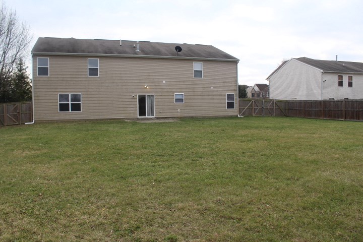 the back of a house with a yard and a fence