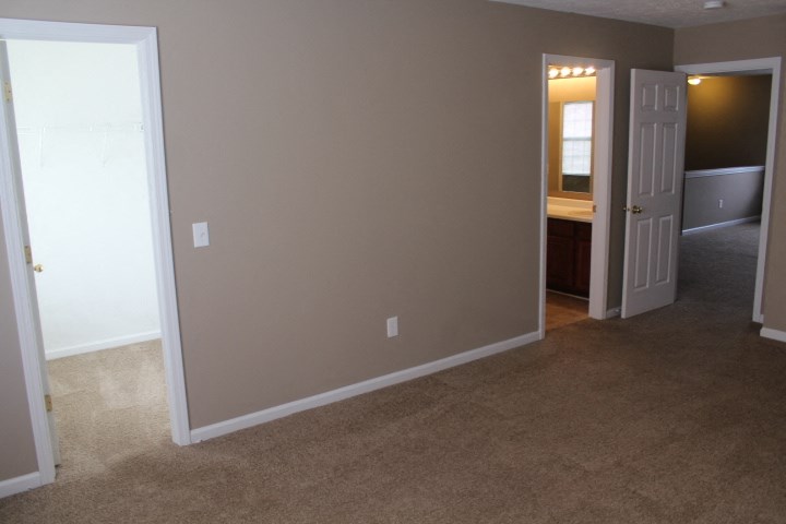 an empty living room with a door into a bathroom