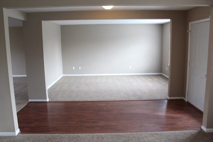 an empty living room with wood floors and a carpet