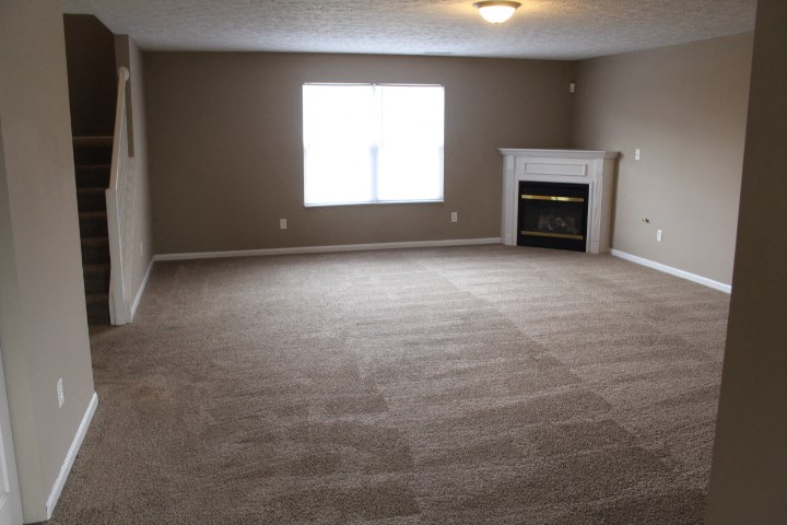 an empty carpeted living room with a fireplace