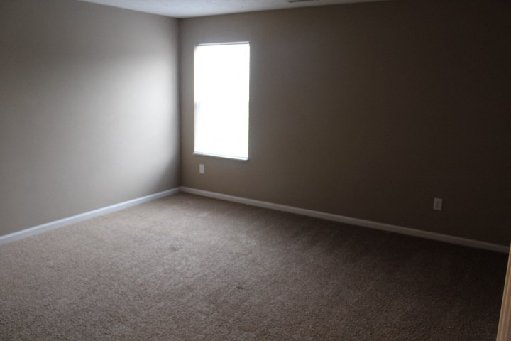 an empty room with a window and carpet