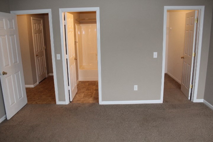 an empty room with three doors and a carpeted floor