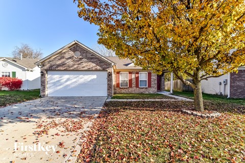 a house with a white garage door and a tree in front of it