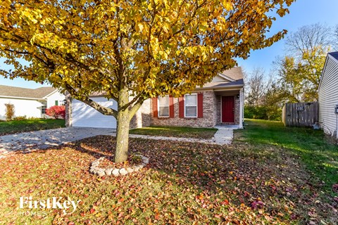 a tree in a yard in front of a house