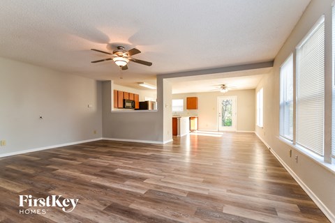 an empty living room with a ceiling fan and a large window