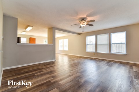 the living room and dining room with wood floors and a ceiling fan