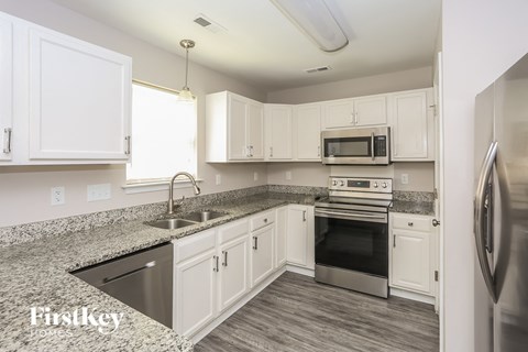 A kitchen with white cabinets and a granite countertop.