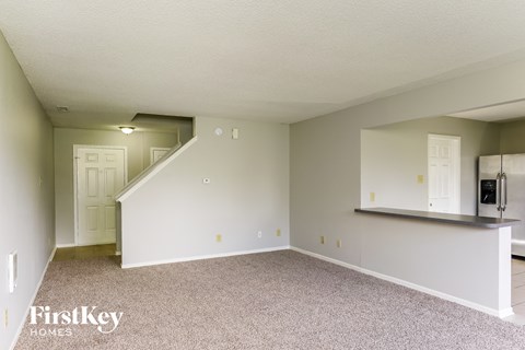 A spacious empty room with a staircase leading to the upper floor.