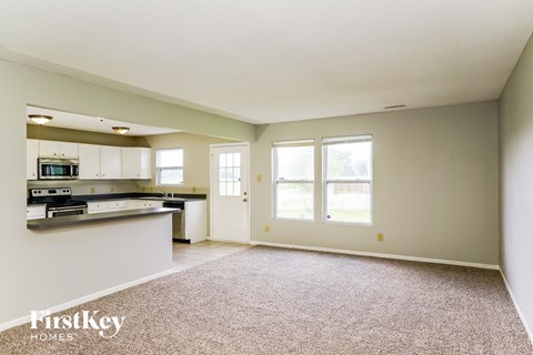 A spacious living room with a kitchen area in the background.