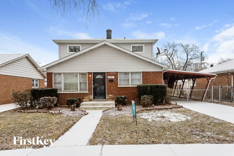 the front of a brick house with snow on the ground