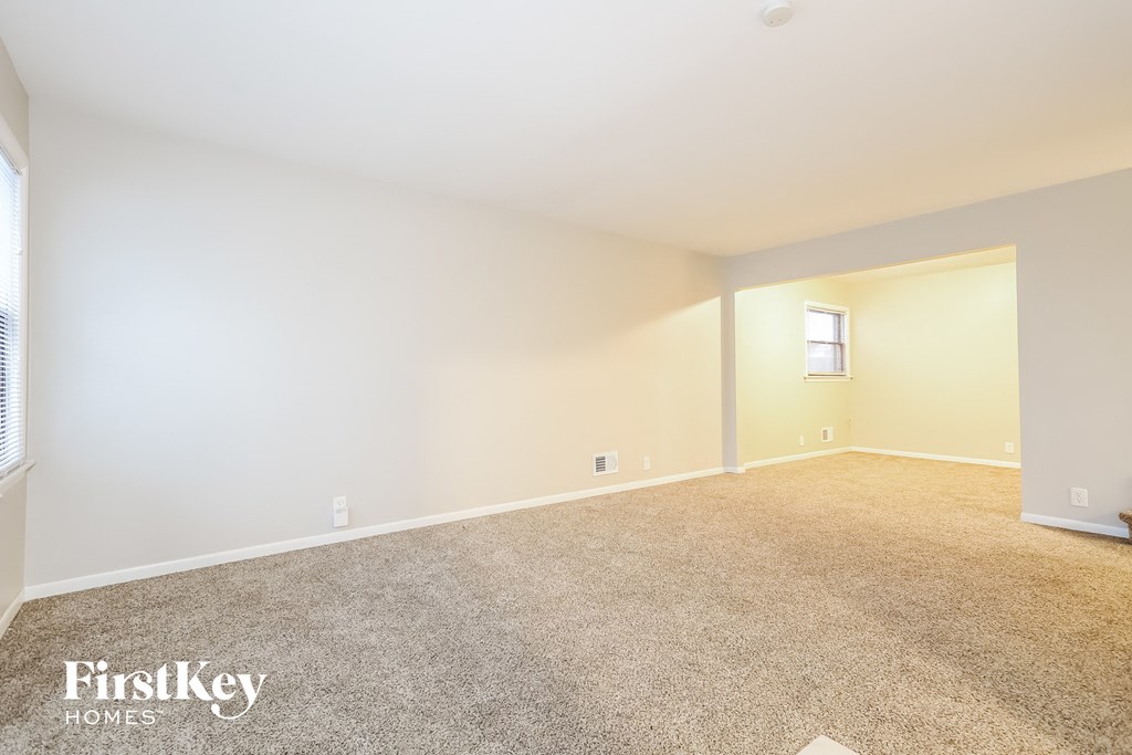 a spacious living room with carpet and white walls