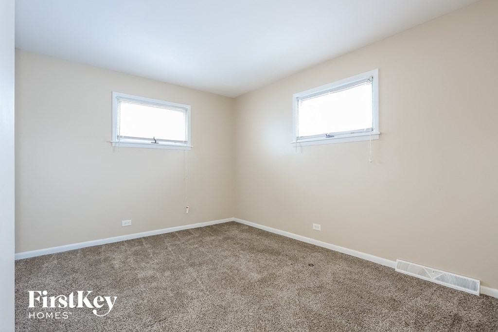 a bedroom with two windows and a carpeted floor