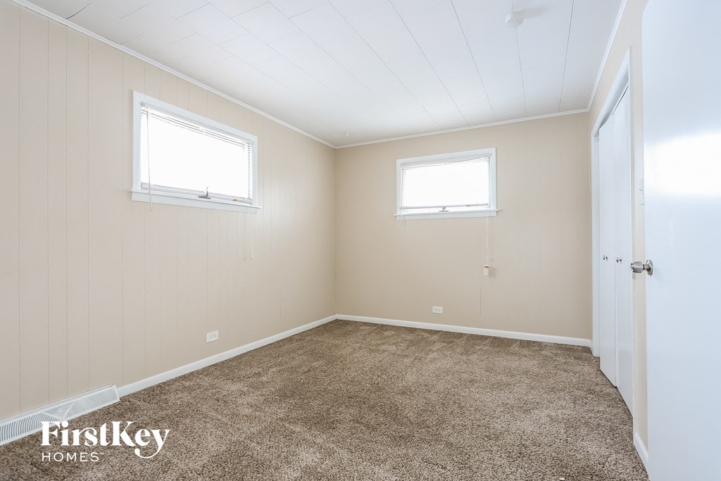 a empty room with carpet and two windows