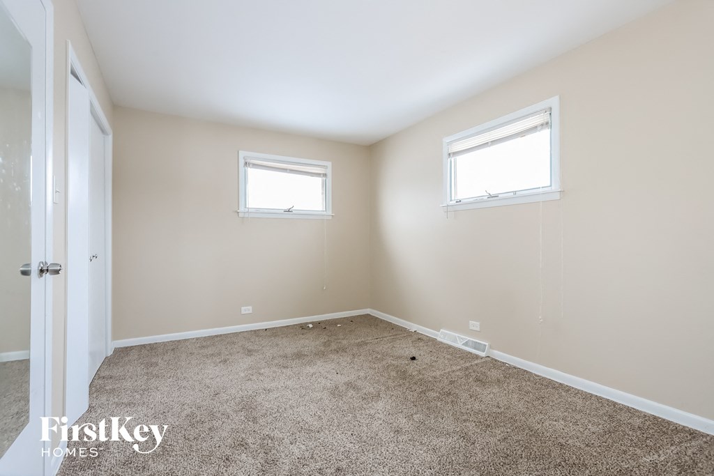 a bedroom with a carpeted floor and two windows