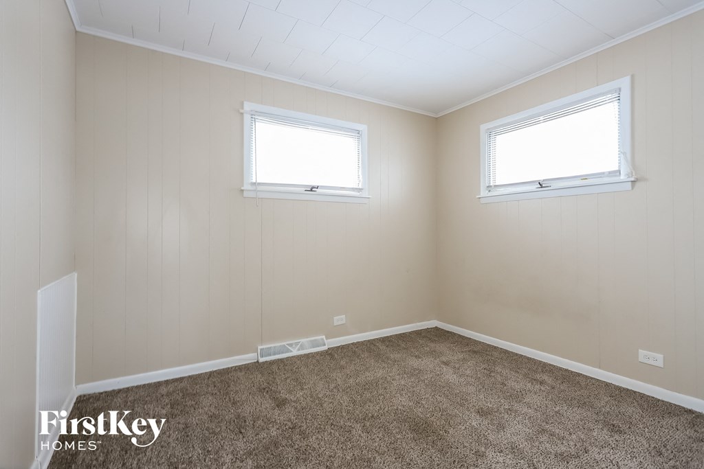 the living room of a home with carpet and two windows