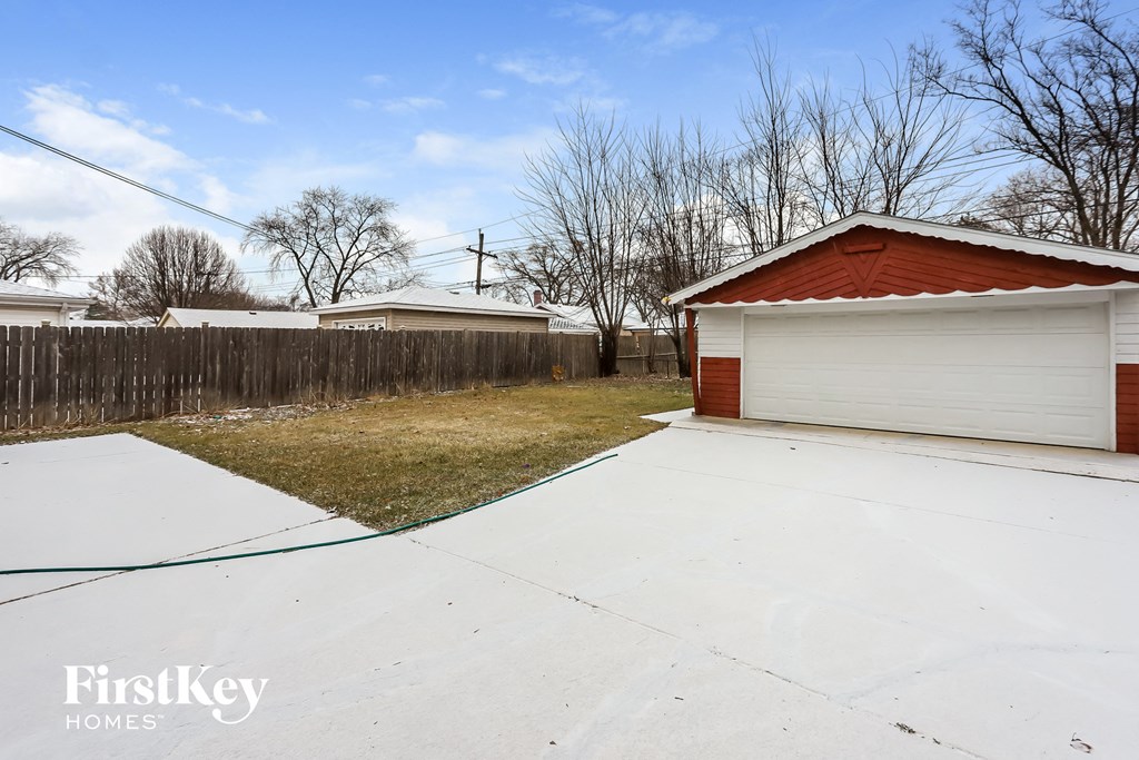 a white garage with a red roof and a white driveway