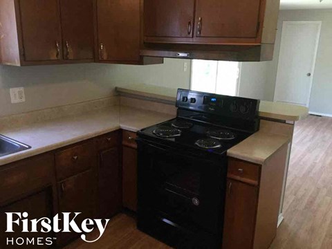 A black stove top oven in a kitchen with wooden cabinets.