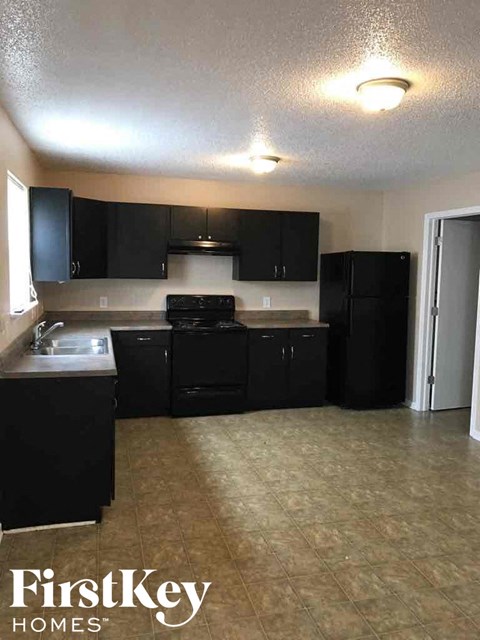 a kitchen with black cabinets and a sink and a refrigerator