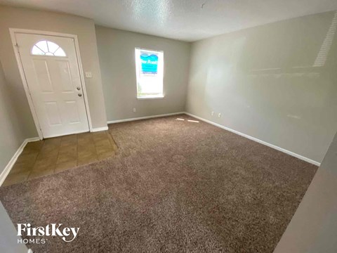 an empty living room with gray carpet and a white door