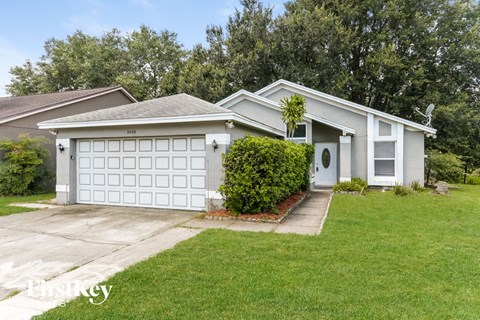 a white house with a white garage door and a lawn