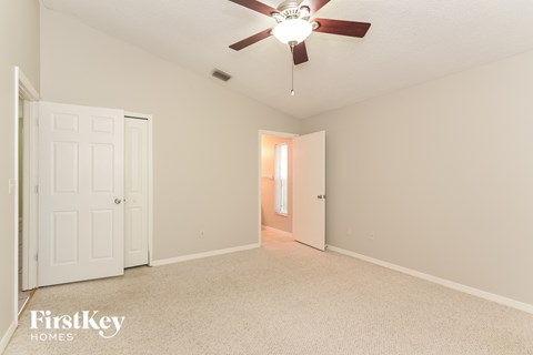 a living room with a ceiling fan and a door to a hallway