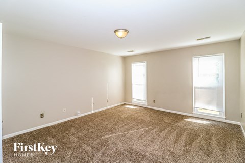 the spacious living room with carpet and two windows