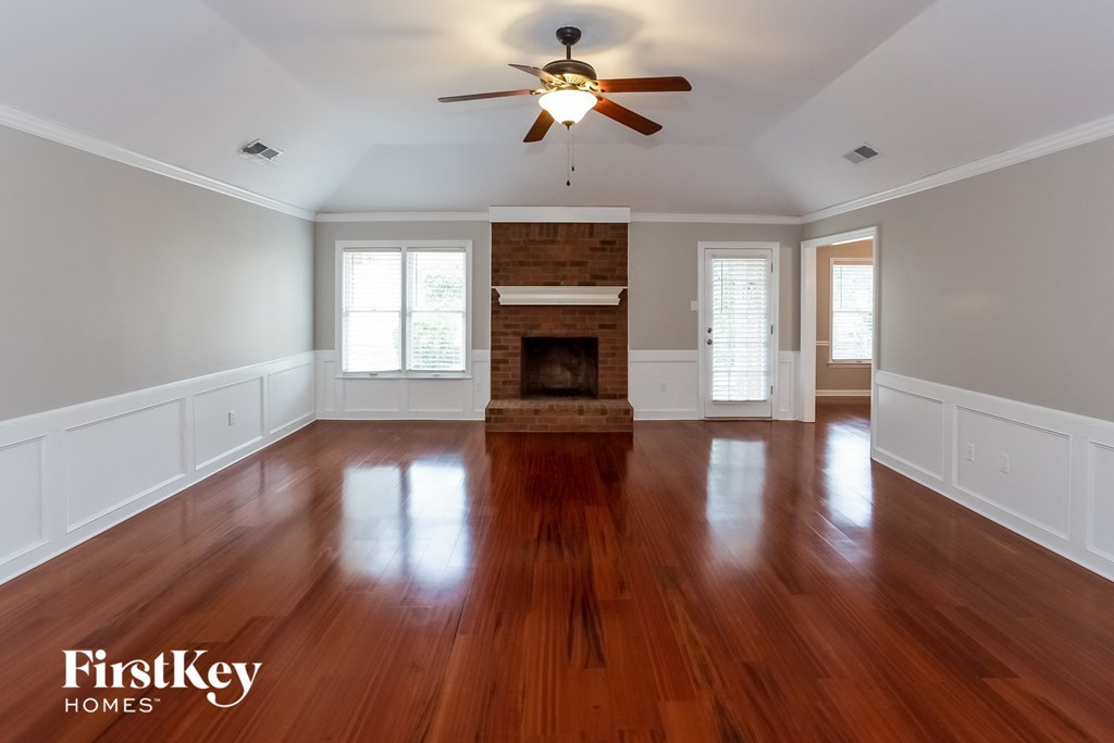 A spacious room with wooden floors and a fireplace.