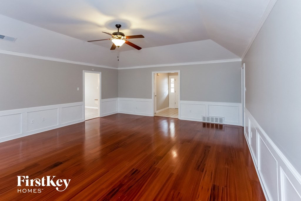A spacious room with wooden floors and a ceiling fan.