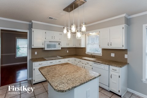 A kitchen with granite countertops and white cabinets.