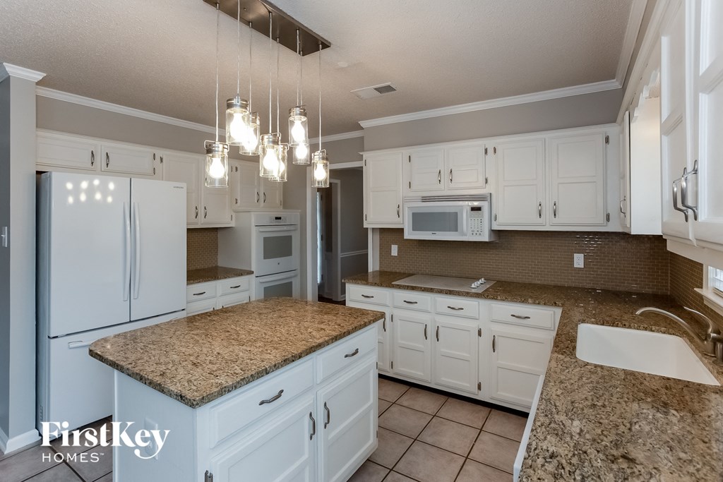 A kitchen with granite countertops and white cabinets.