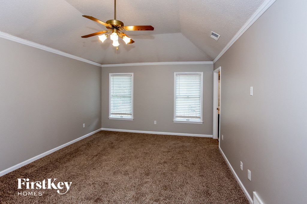 A room with a ceiling fan and carpeted floor.
