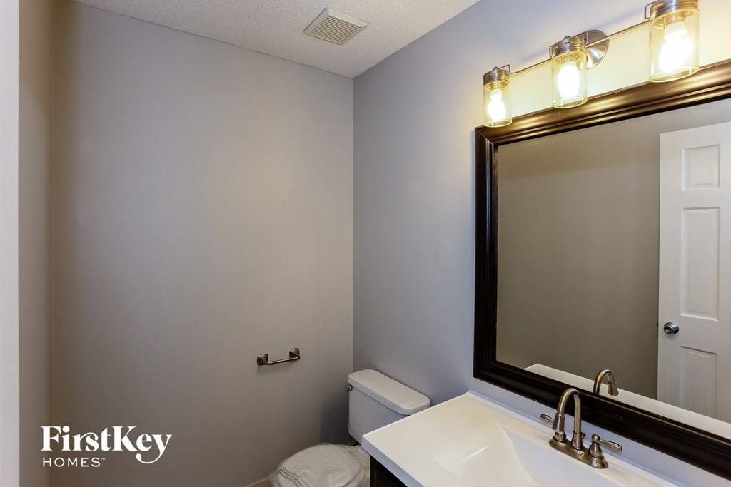 A bathroom with a toilet, sink and mirror.