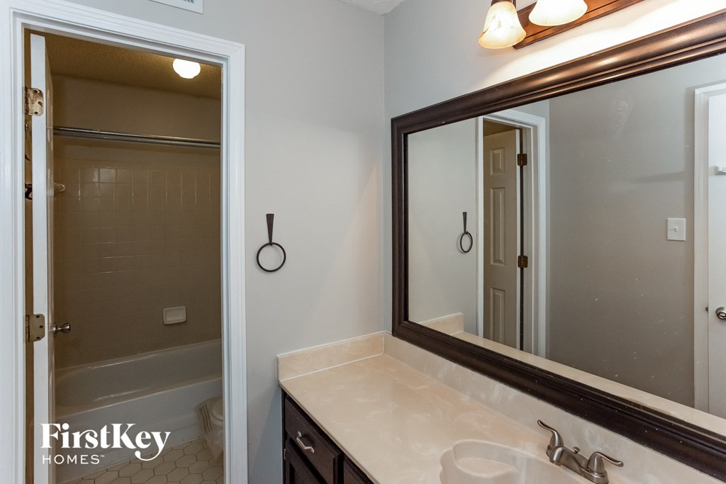 A bathroom with a sink, mirror, and shower.