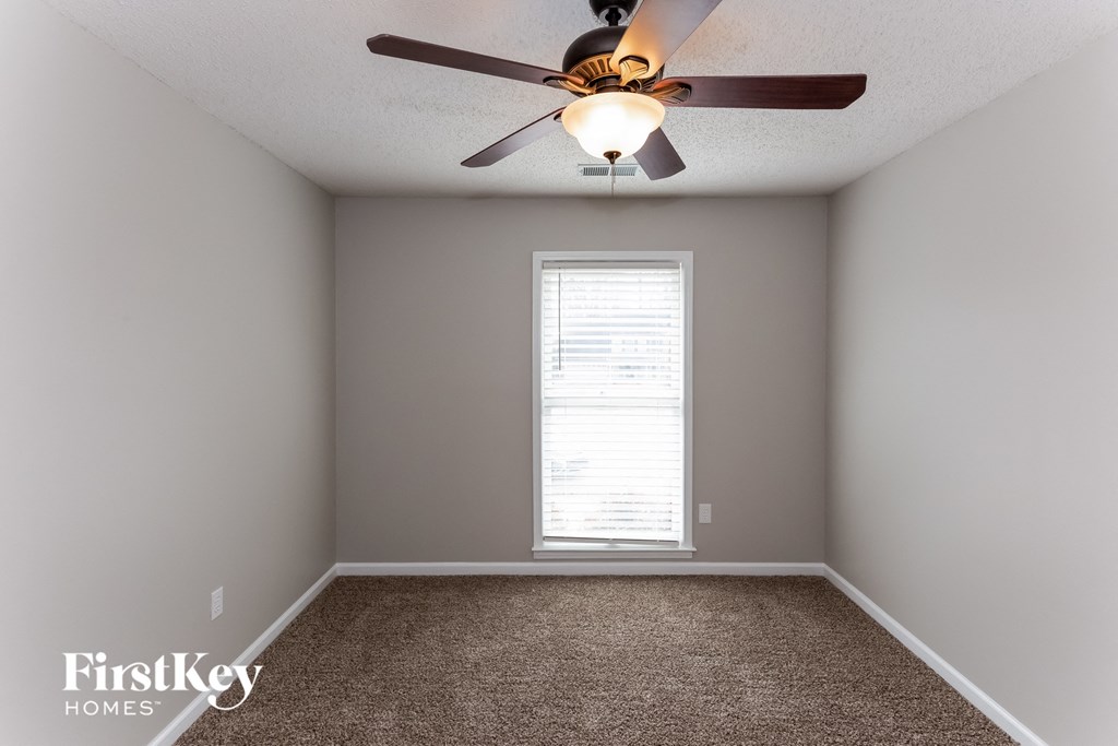 A room with a ceiling fan and a window with blinds.
