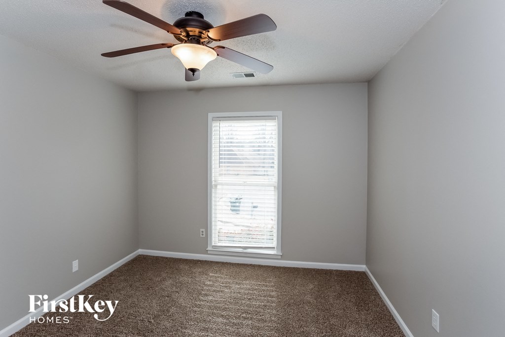 A room with a ceiling fan and a window with blinds.