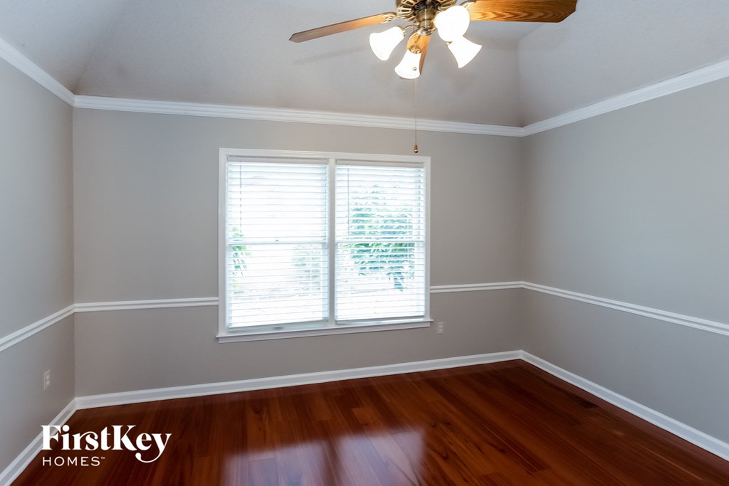 A room with a ceiling fan and a window with blinds.
