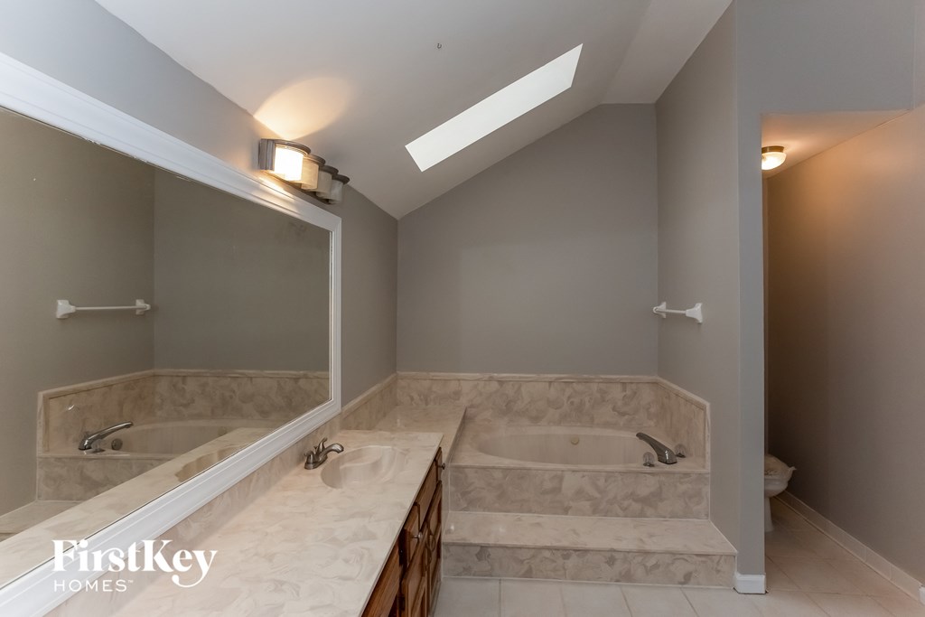A bathroom with a skylight and a marble countertop.