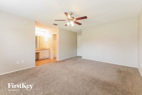 a spacious living room with carpet and a ceiling fan