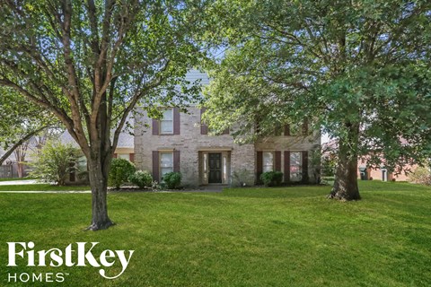 A house with a lawn and trees in front of it.