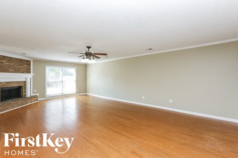 A spacious room with a fireplace and a ceiling fan.