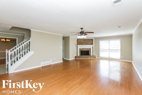 A spacious living room with a fireplace and a staircase.