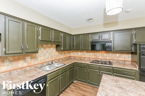 A kitchen with green cabinets and a marble countertop.