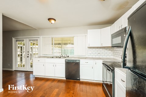 A kitchen with white cabinets and black appliances.