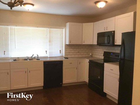 A kitchen with black appliances and white cabinets.