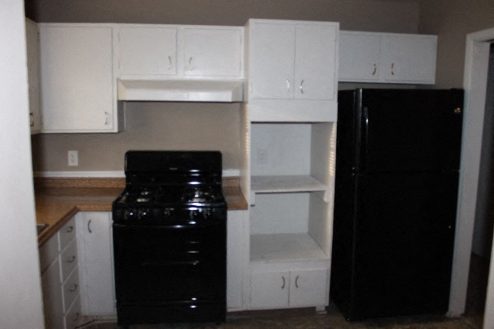 A black refrigerator sits next to a black stove in a kitchen.