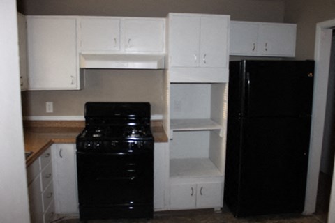 A black refrigerator sits next to a black stove in a kitchen.